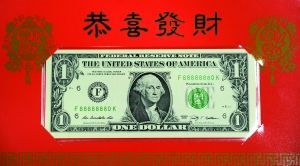 1美元的“吉利钱”纸币收藏在一枚大红套封中，套封外面印有金马腾跃图案，旁边印有中英文“吉利钱”字样和中文“马到成功”。 新华社发